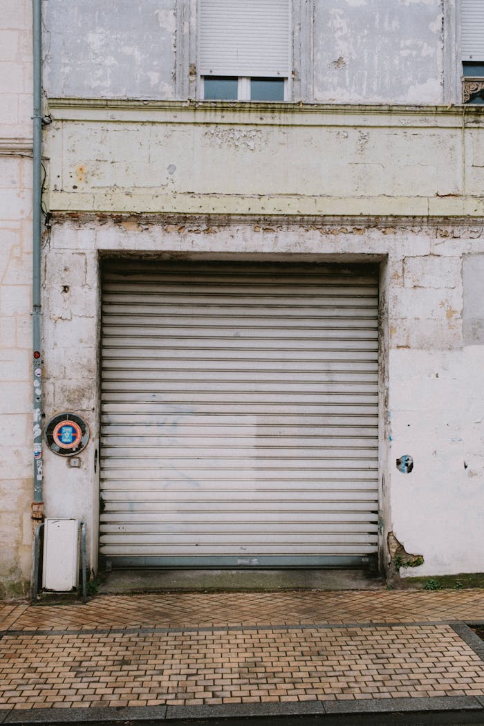 An old garage door with a weathered wall, showcasing urban decay and texture.